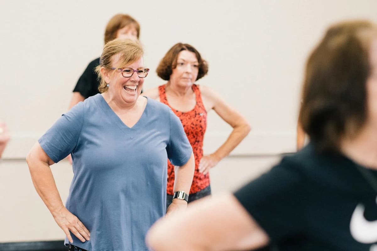 Happy middle-aged women laughing together during a group fitness class